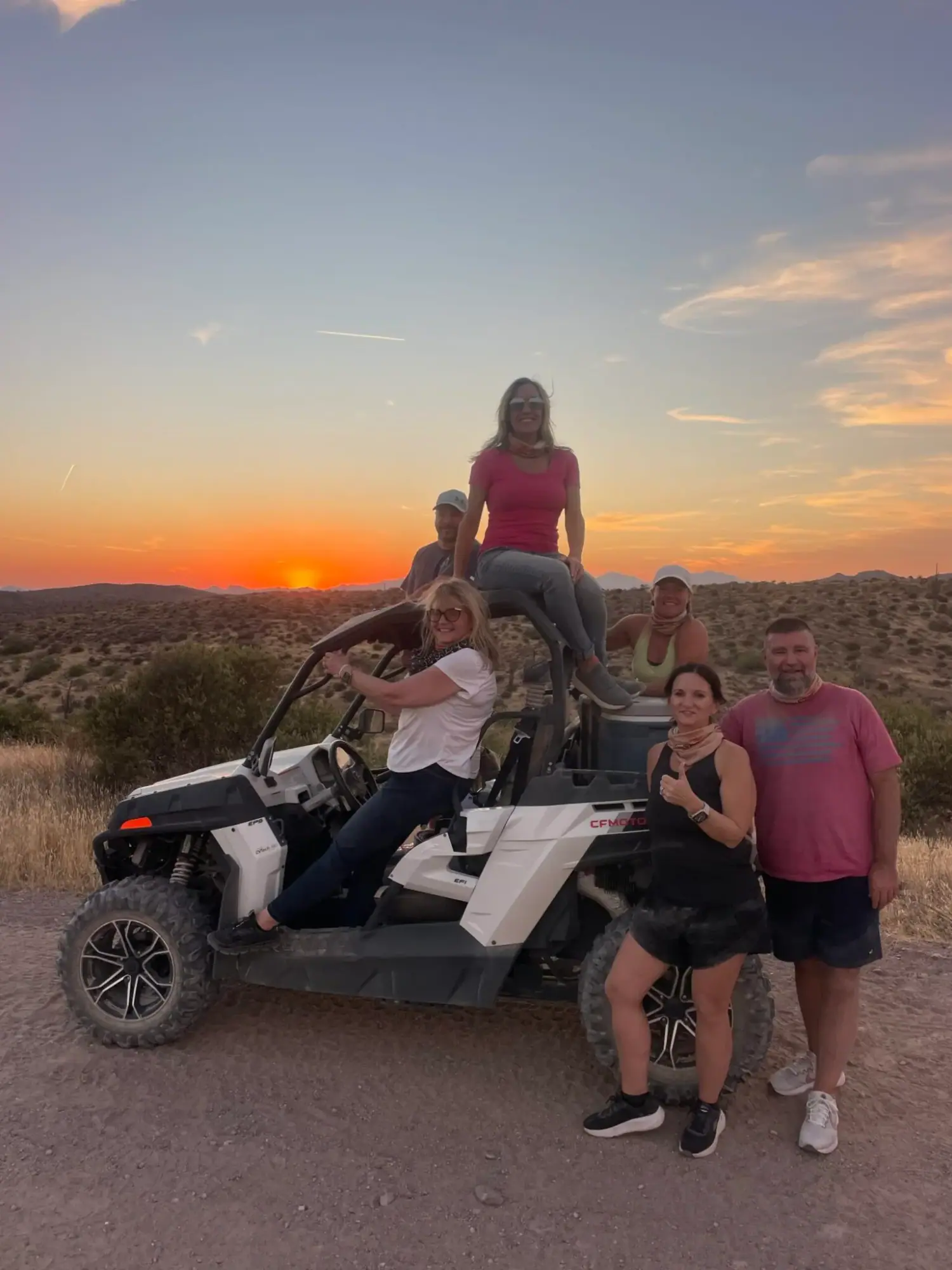 A private VIP tour group poses on and around their buggy as the sun sets over the Sonoran Desert near Scottsdale